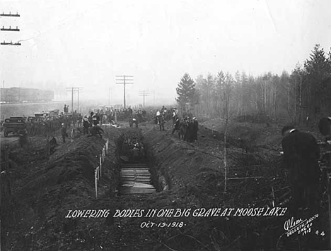 Lowering bodies of fire victims into one long grave, Moose Lake Minnesota, 1918