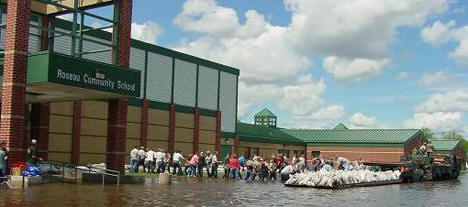 Volunteers building a sandbag dike around the Roseau Community School, 2002