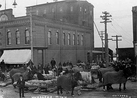 Horse drawn sleds with loads in front of a Wabasha building, Wabasha Minnesota, 1910