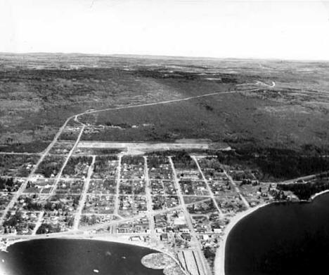 Aerial view of Grand Marais on the north shore of Lake Superior, white line is the Gunflint Trail, 1955